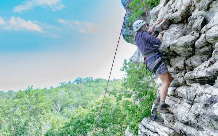 girl rock climbs on outdoor expedition near baltimore